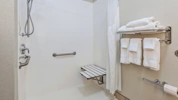 A shower area with a glass door, a towel rack with multiple towels, and a small shelf.