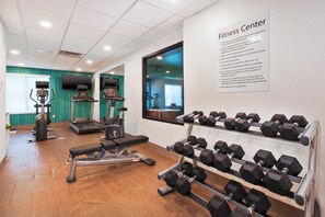 Un centre de remise en forme équipé de tapis de course, de vélos elliptiques et d’une série d’haltères.