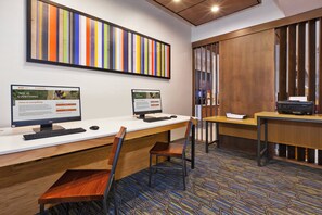 A modern office space with two desks, computers, and a large colorful artwork on the wall.