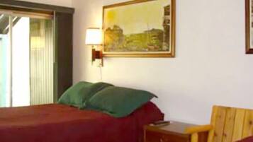 Een hotelkamer met een bed, nachtkastje, lamp en een schilderij aan de muur.