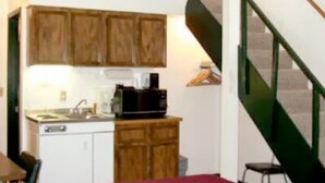 Une cuisine de taille réduite, avec des meubles de rangement en bois, un évier et une machine à café.