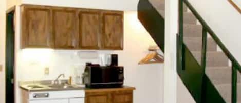 A compact kitchen with wooden cabinets, a sink, and a coffee maker.