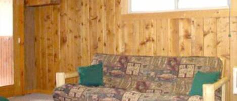 A wooden cabin interior with a sofa and two pillows.