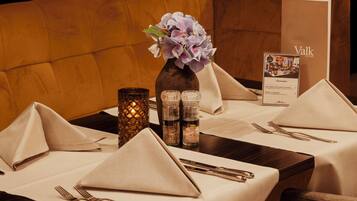 A dining table set with a vase of flowers, salt and pepper shakers, and a menu.