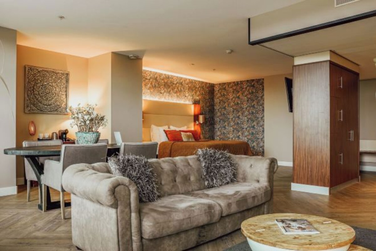 A modern living room with a sofa, coffee table, and a dining area with a table and chairs.