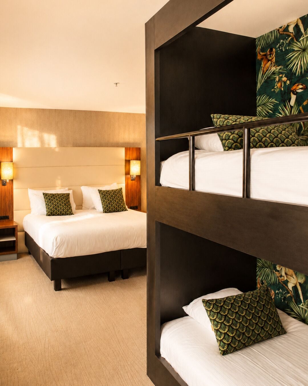 A hotel room with a bunk bed, a separate bed, and a headboard with wall-mounted lamps.
