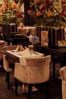 Un ambiente de restaurante con mesas dispuestas para comer, adornadas con diversos floreros y velas.