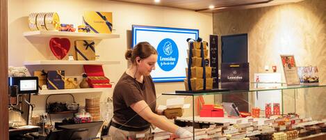 A chocolate shop interior with a display of assorted chocolates and a sign for Leonidas chocolates.