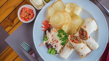 Un plato con un wrap, papas fritas y una ensalada pequeña.
