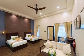 A hotel room with two beds, a sofa, a desk, and a ceiling fan. - Mayang Sari Beach Resort (Bintan)