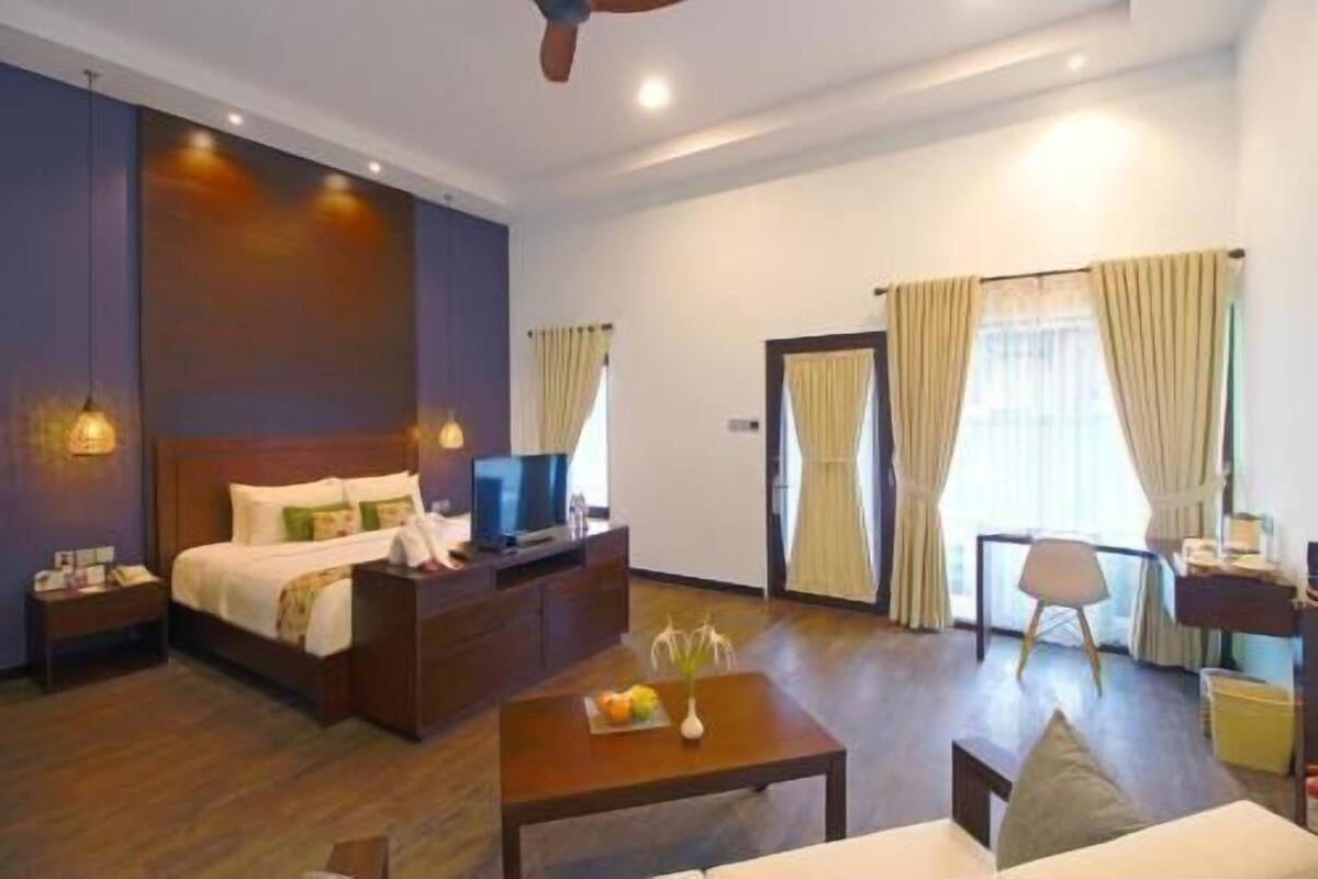 Une chambre d’hôtel comprenant un lit, un bureau, une chaise, une table basse et un téléviseur.