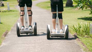 Two people on segways on a paved path in a park.