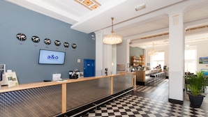 A reception area with a checkered floor, a reception desk, a blue door, and a chandelier. - a&o Leipzig Hauptbahnhof (Leipzig)