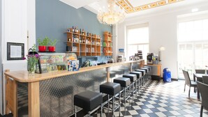A bar area with a checkered floor, bar stools, a wine and liquor shelf, and a chandelier. - a&o Leipzig Hauptbahnhof (Leipzig)