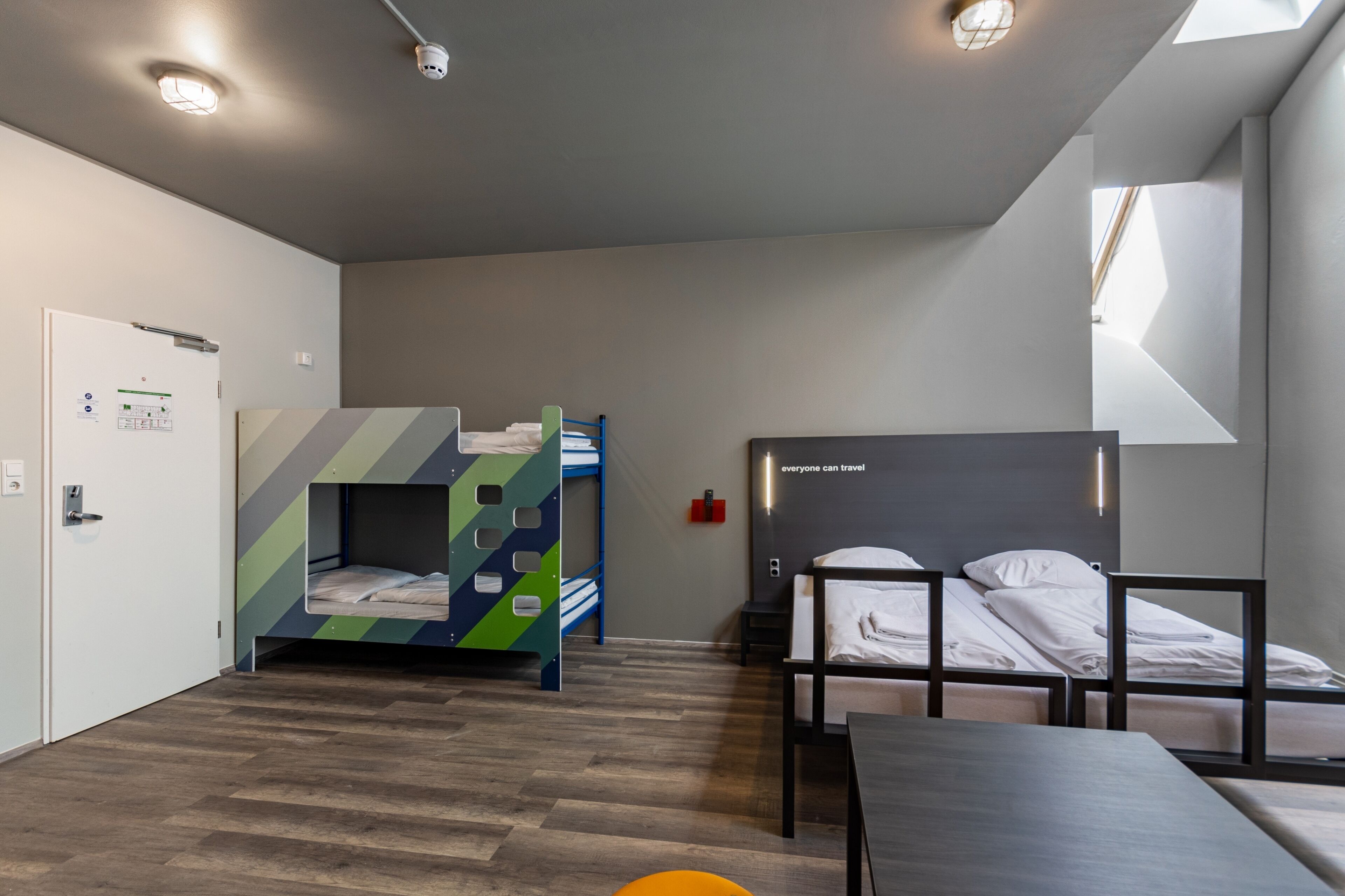 Una habitación de hotel moderna con literas, un escritorio y una ventana que proporciona luz natural.