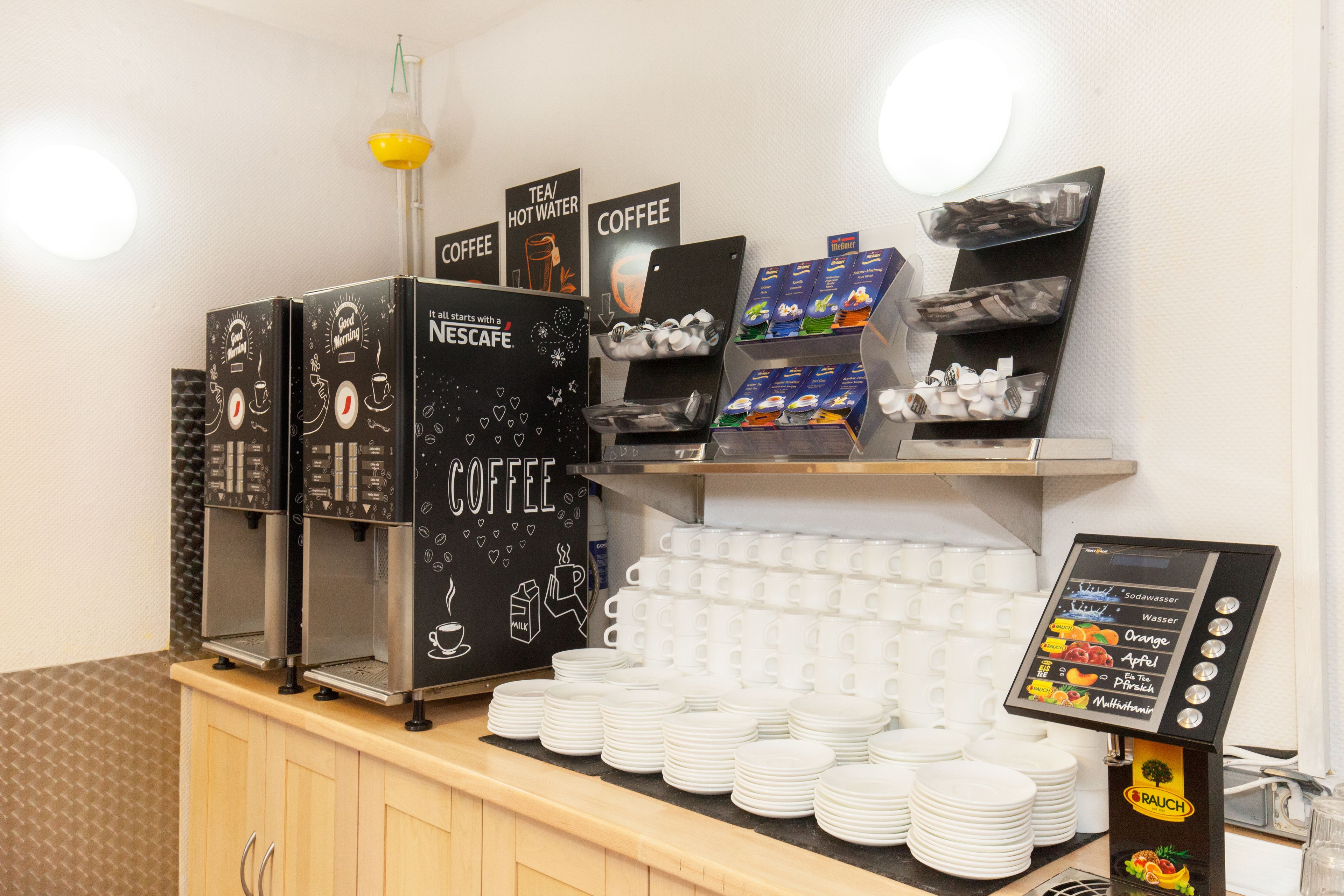 Uma estação de café com várias máquinas de café, um quadro de cardápio e pilhas de copos descartáveis.