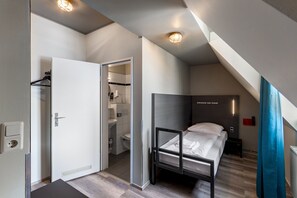 Una habitación de hotel moderna con una cama litera, un vestidor y un baño con inodoro y lavabo.