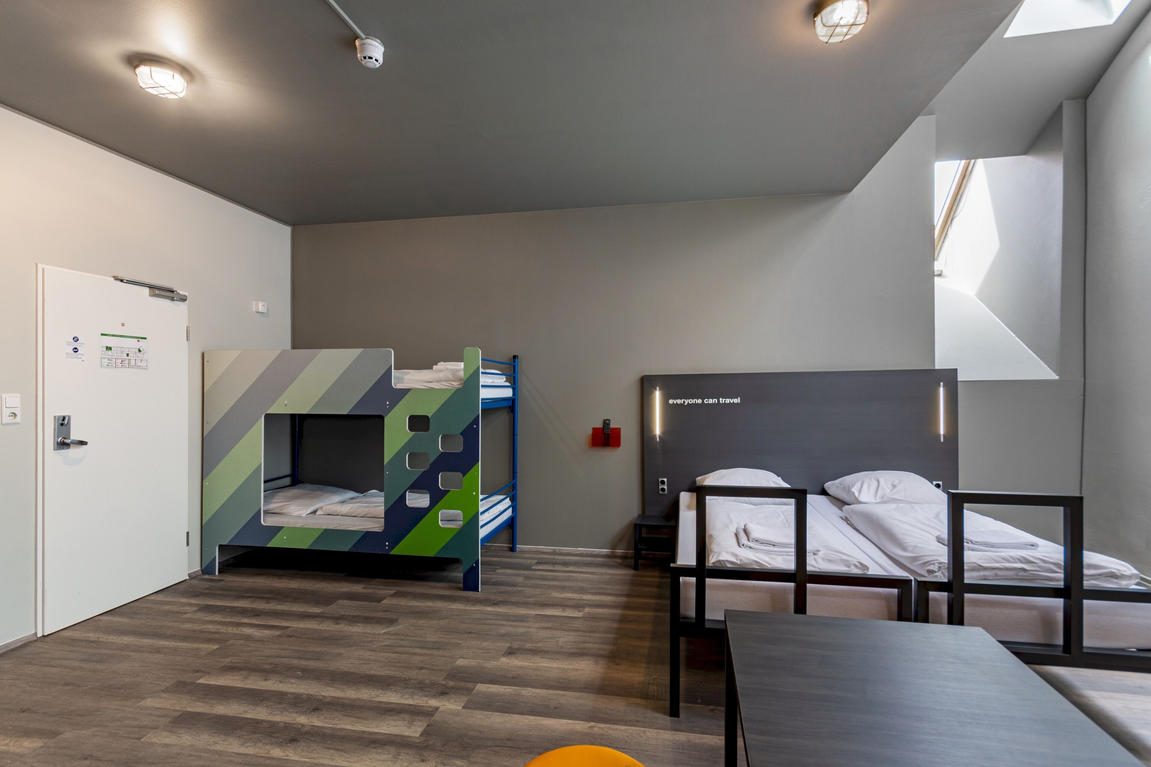 Habitación de hotel moderna con literas, un escritorio y una ventana que proporciona luz natural.
