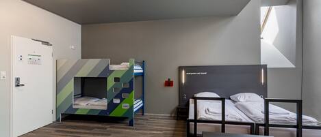 A modern hotel room with bunk beds, a desk, and a window providing natural light.