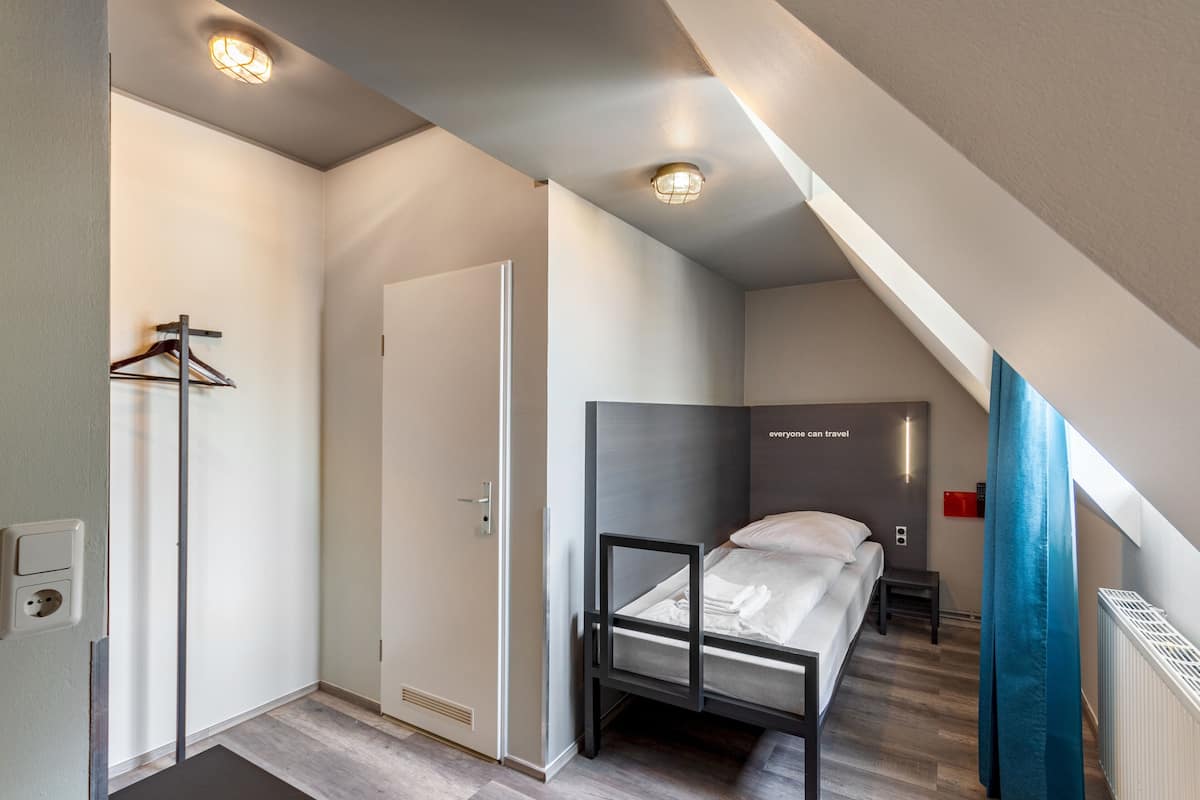 A small, modern bedroom with a bunk bed, a wardrobe, and a shower area.