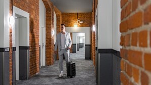 A hotel corridor with brick walls, white doors, and numbered room signs. - a&o Leipzig Hauptbahnhof (Leipzig)