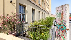 A building with multiple windows, a balcony with a potted plant, and a wall with graffiti. - a&o Leipzig Hauptbahnhof (Leipzig)