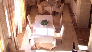 A dining area with a chandelier, round table, chairs, and a staircase. - Hacienda Los Jinetes (Carmona)