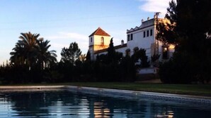 A swimming pool with a building in the background. - Hacienda Los Jinetes (Carmona)