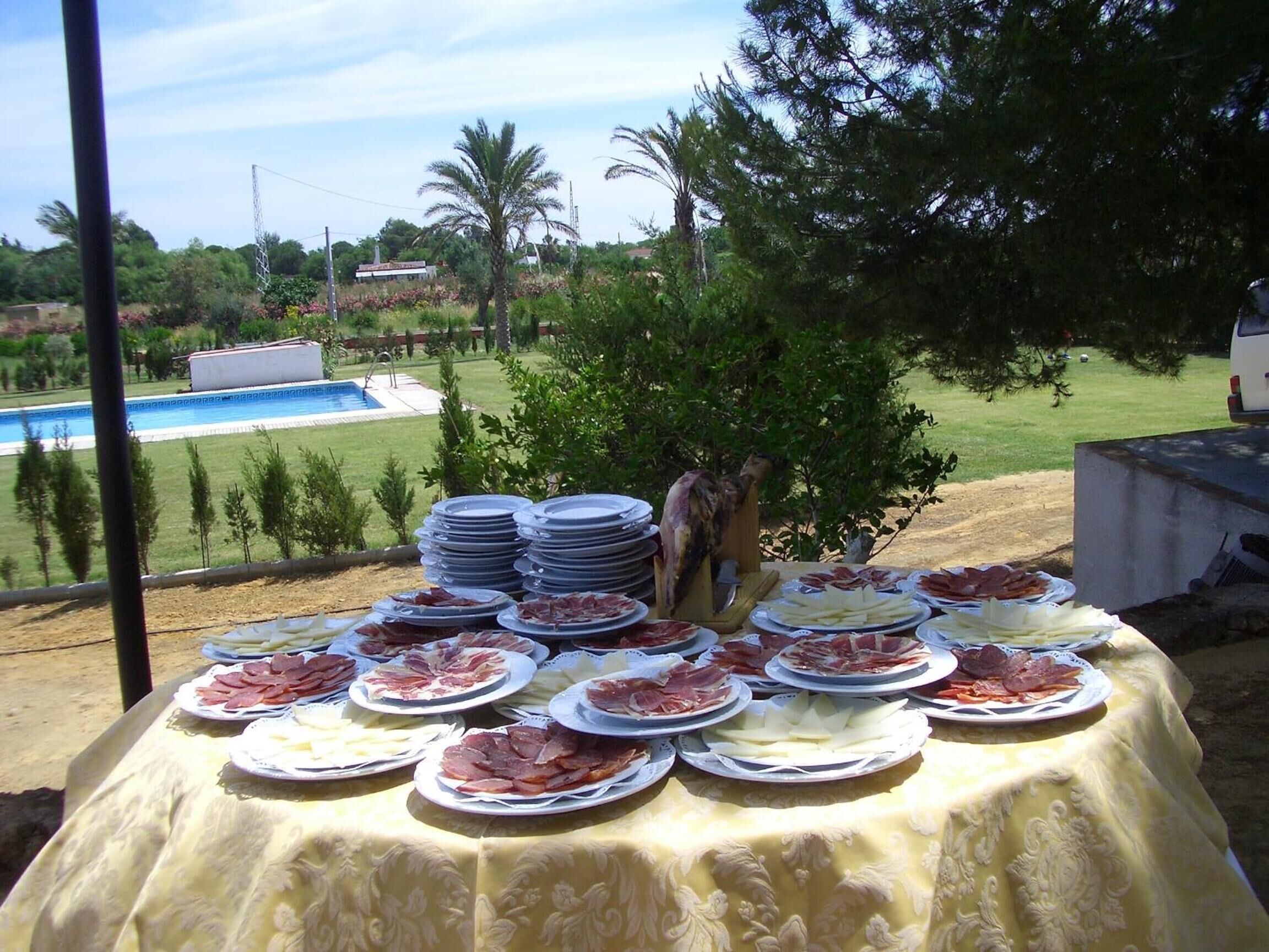 An outdoor buffet table with various food items and a pool in the background.