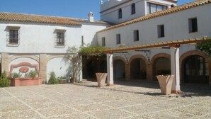 A courtyard with a tiled floor, white walls, and a pergola structure. - Hacienda Los Jinetes (Carmona)