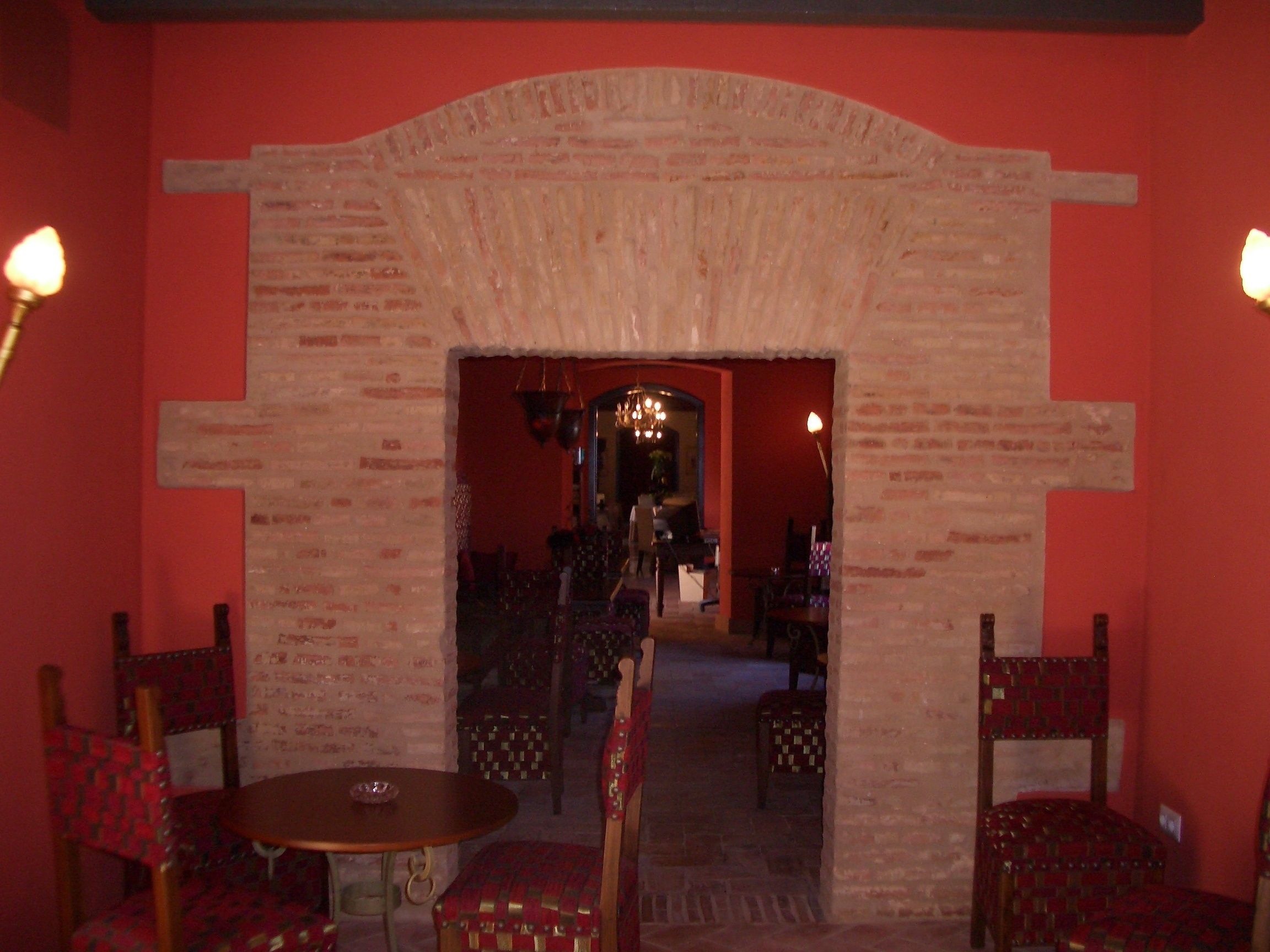 A room with a brick archway leading to a dining area with a table and chairs.