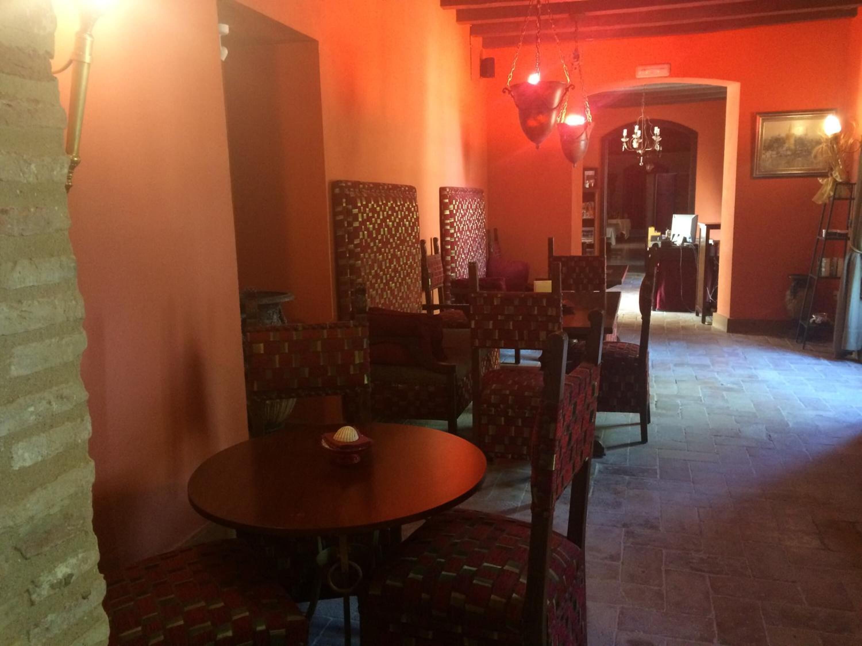 A dining area with brick walls, patterned chairs, and a round table.