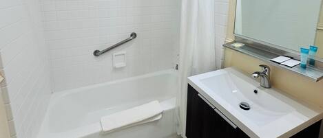 A bathroom with a bathtub, a sink, a mirror with lights, and a shower curtain.