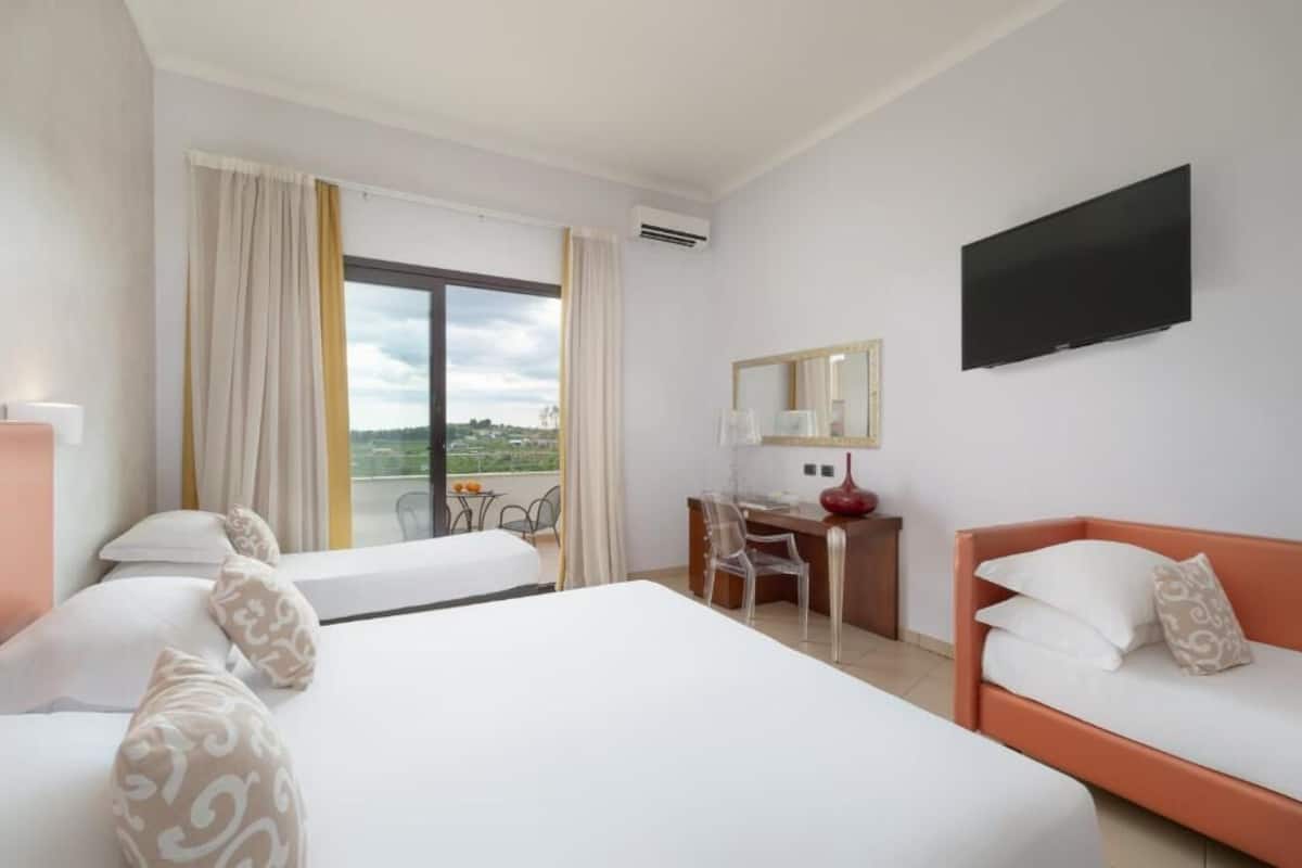 Une chambre d’hôtel avec deux lits, un bureau, une télévision et un balcon avec vue.
