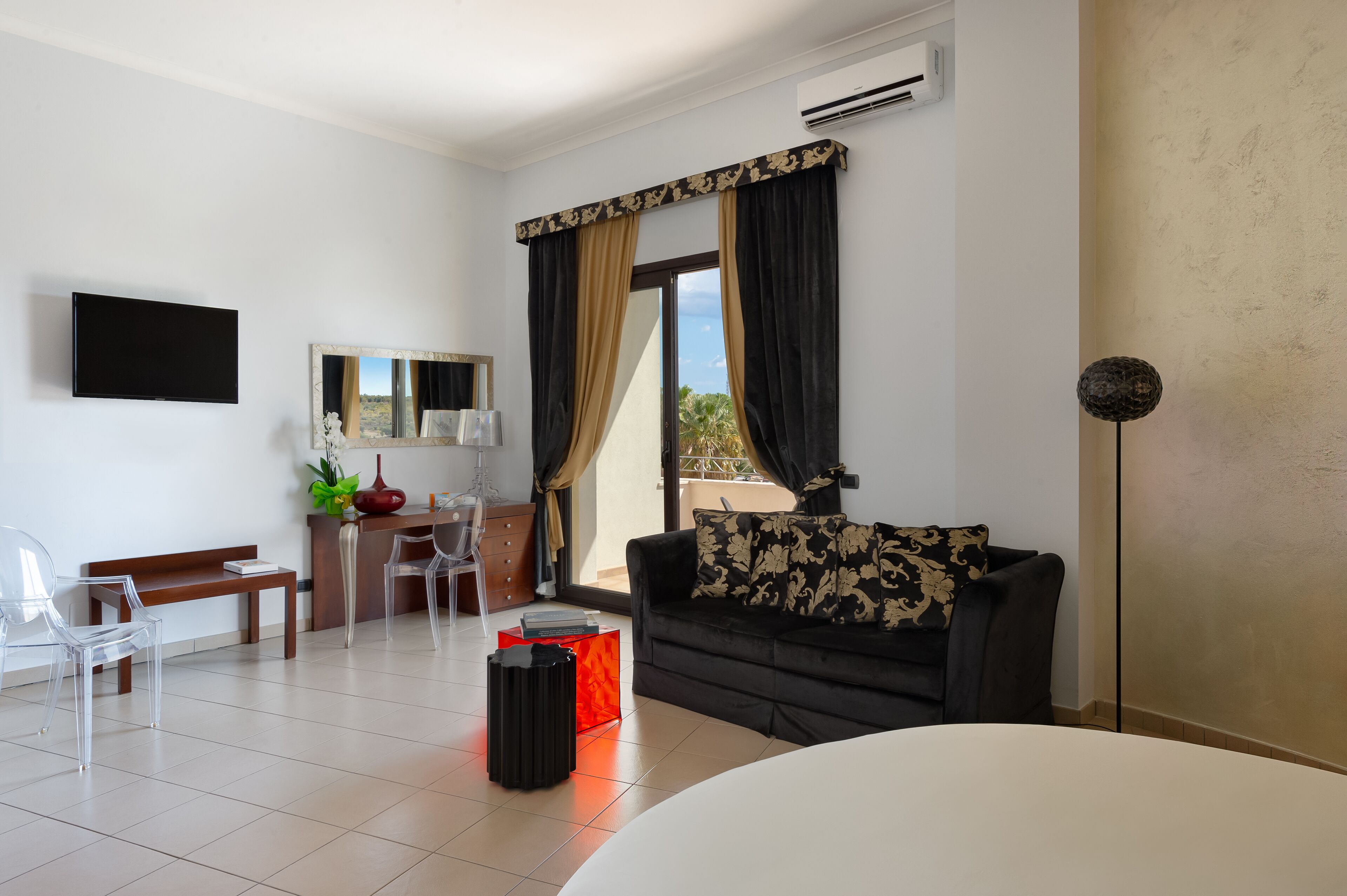 A modern living room with a sofa, a TV, a dining table, and a large window with curtains.