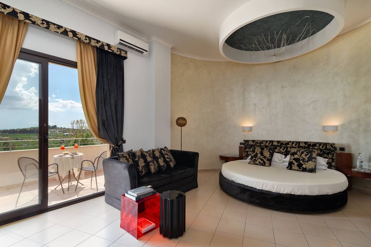 Une chambre d’hôtel moderne dotée d’un grand lit, d’un canapé, d’une table à manger et d’un balcon avec vue.