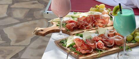 A table with a charcuterie board, two drinks, and a folded towel on a white table.