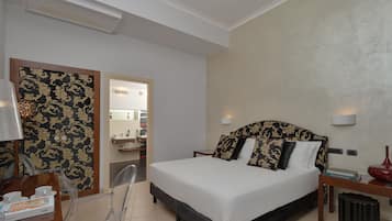 Una camera d'albergo con un letto, un comodino, una lampada e una scrivania con una sedia.