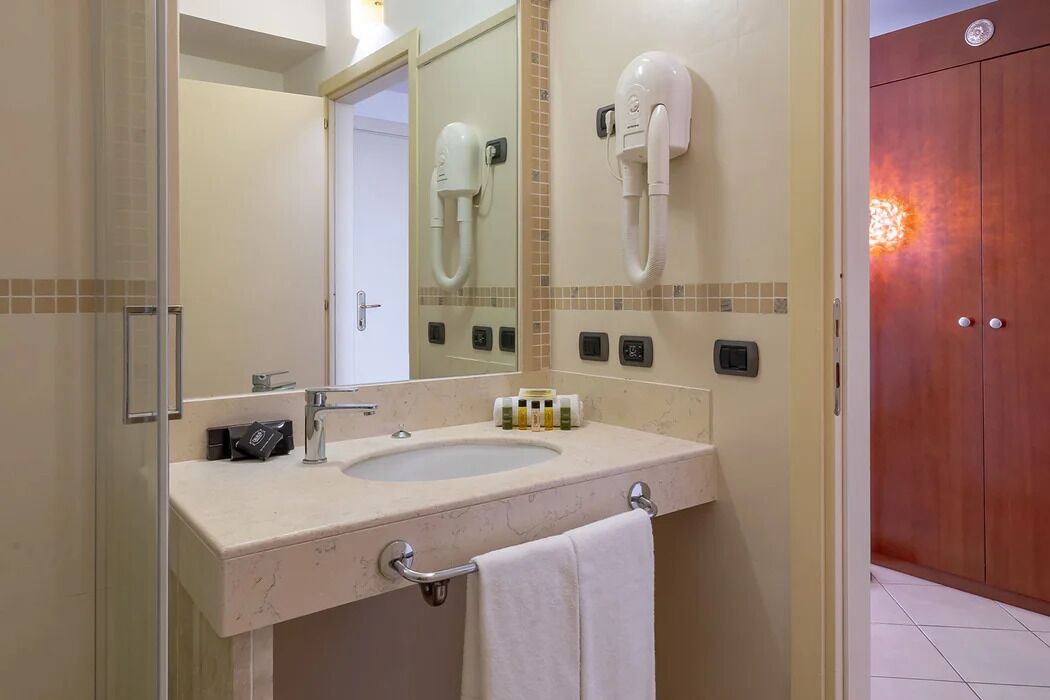 A bathroom with a sink, mirror, hairdryer, and towel rack.