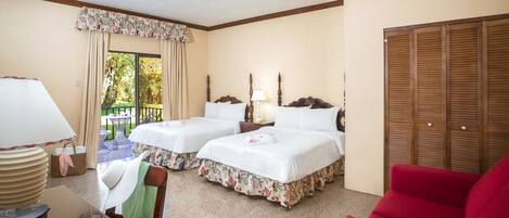 A hotel room with two beds, a red sofa, a table with a coffee maker, and a view of the outdoors.