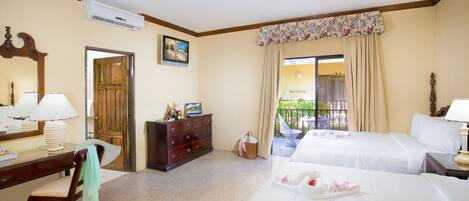 A hotel room with two beds, a desk, a dresser, a mirror, and a window with curtains.