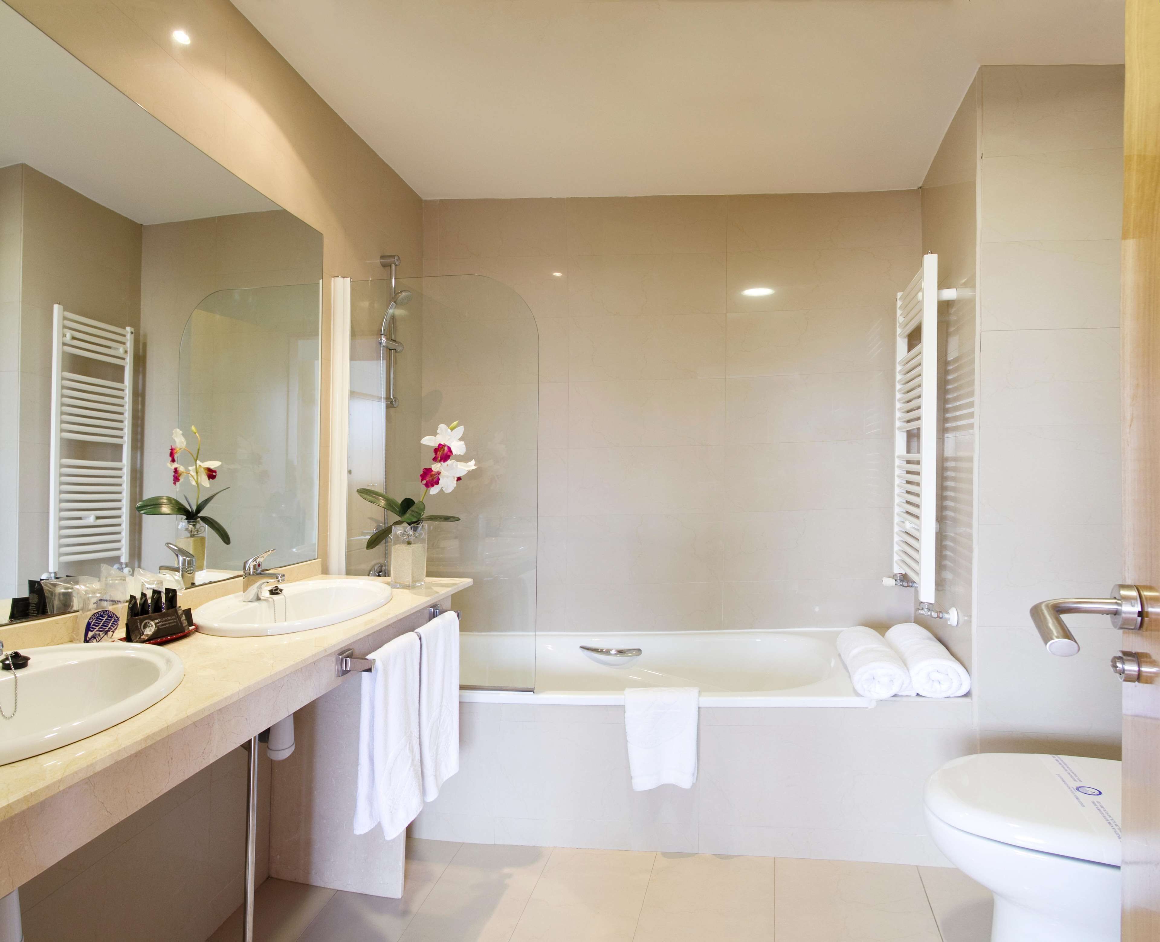 Un baño moderno con bañera, lavamanos, inodoro y mampara de cristal.