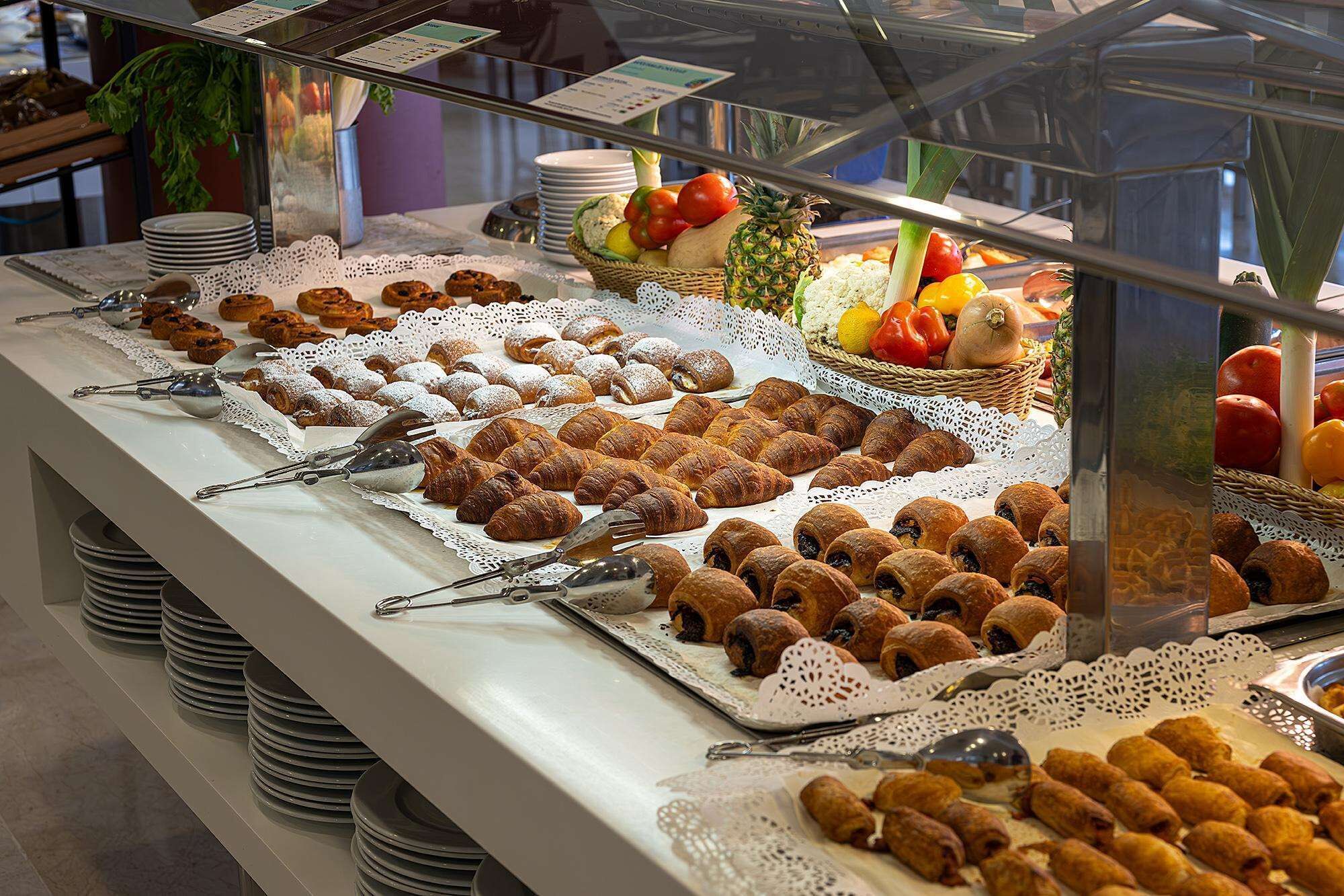 Un bufé con diversos pasteles, frutas y verduras.