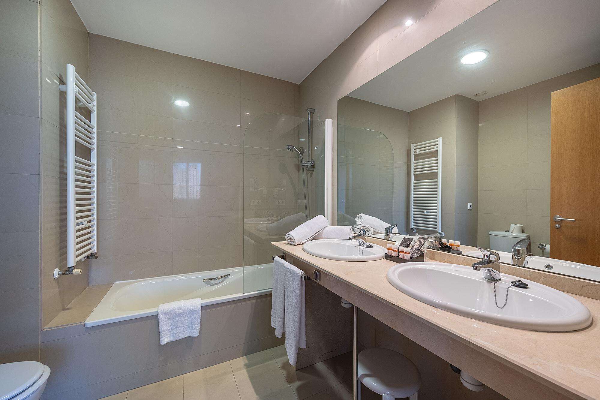 A modern bathroom with two sinks, a bathtub, and a shower.