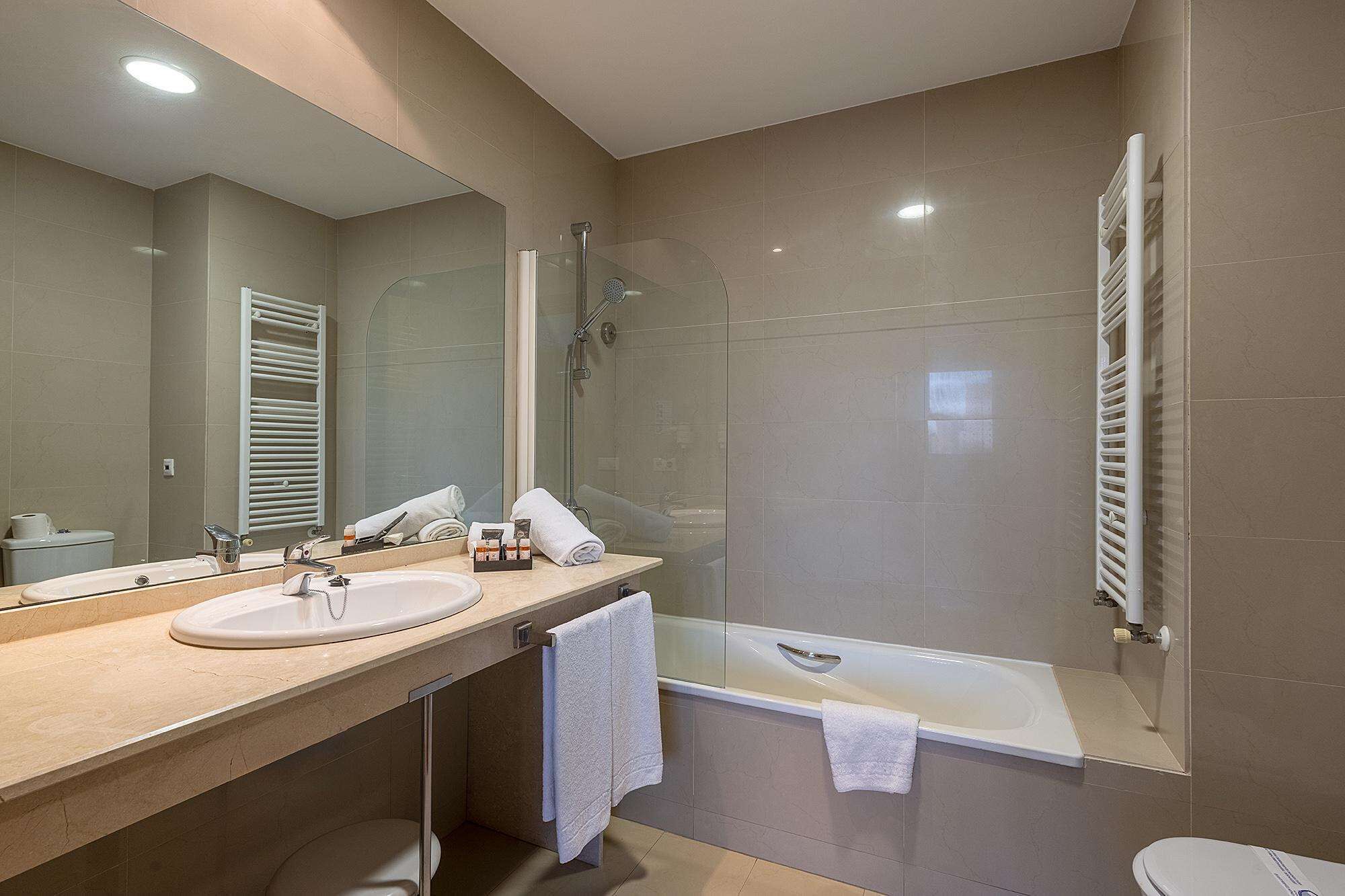 A modern bathroom with a sink, mirror, shower, and bathtub.