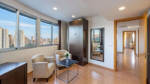 Un apartamento moderno con ventanas grandes, vista a la ciudad, comedor y pasillo que conduce a otra habitación.