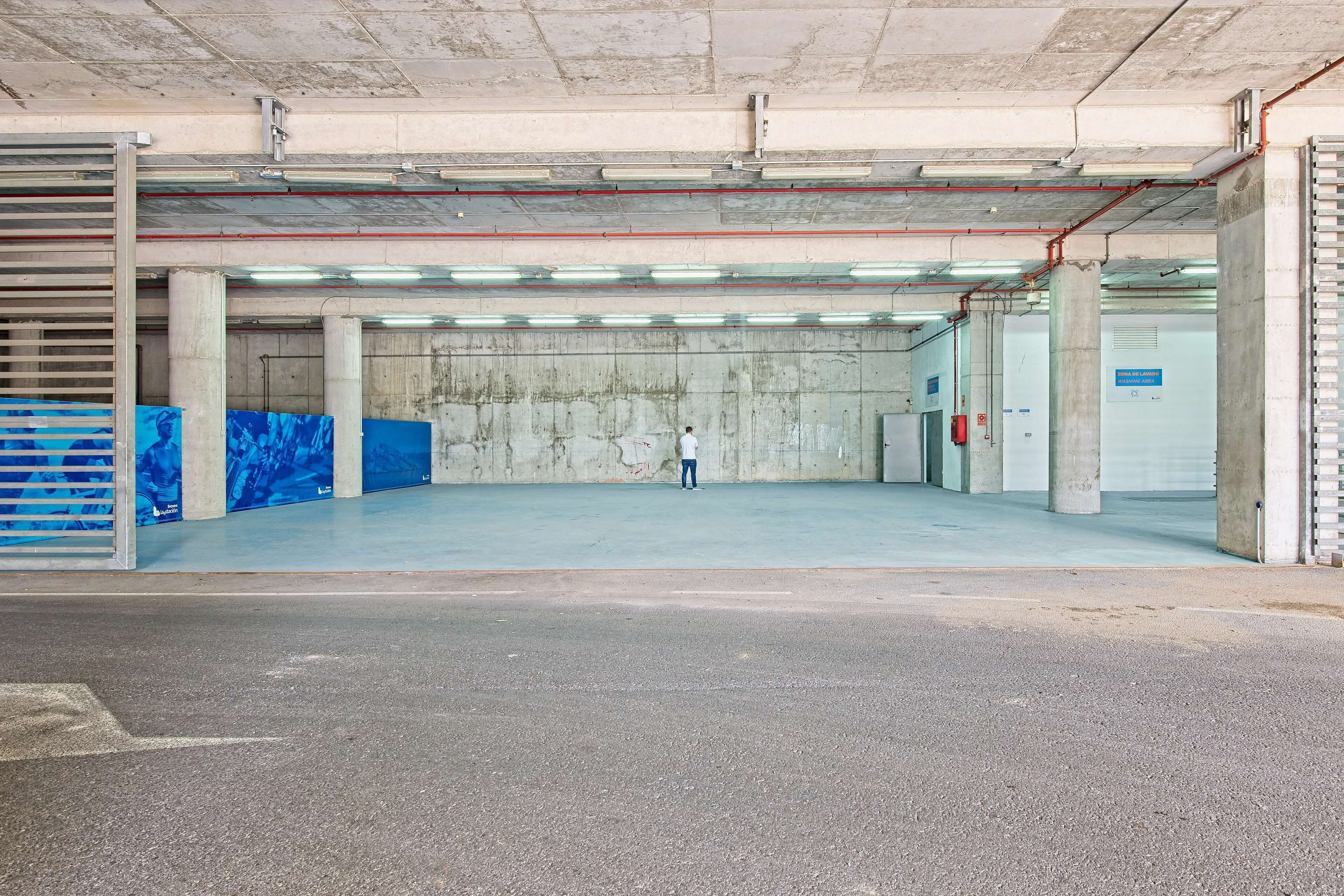 Un vaste parking souterrain, vide, avec des piliers en béton et un éclairage fluorescent.