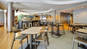 A modern restaurant with round tables, bar seating, and a counter area. - SpringHill Suites Tallahassee Central (Tallahassee)