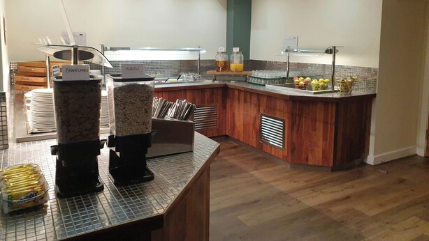 A modern kitchen with a breakfast bar, coffee machines, and a fruit display. - Legacy Preston International Hotel (Preston)