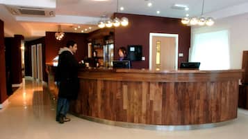 A reception area with a wooden counter, a television, and a ceiling with multiple light fixtures.